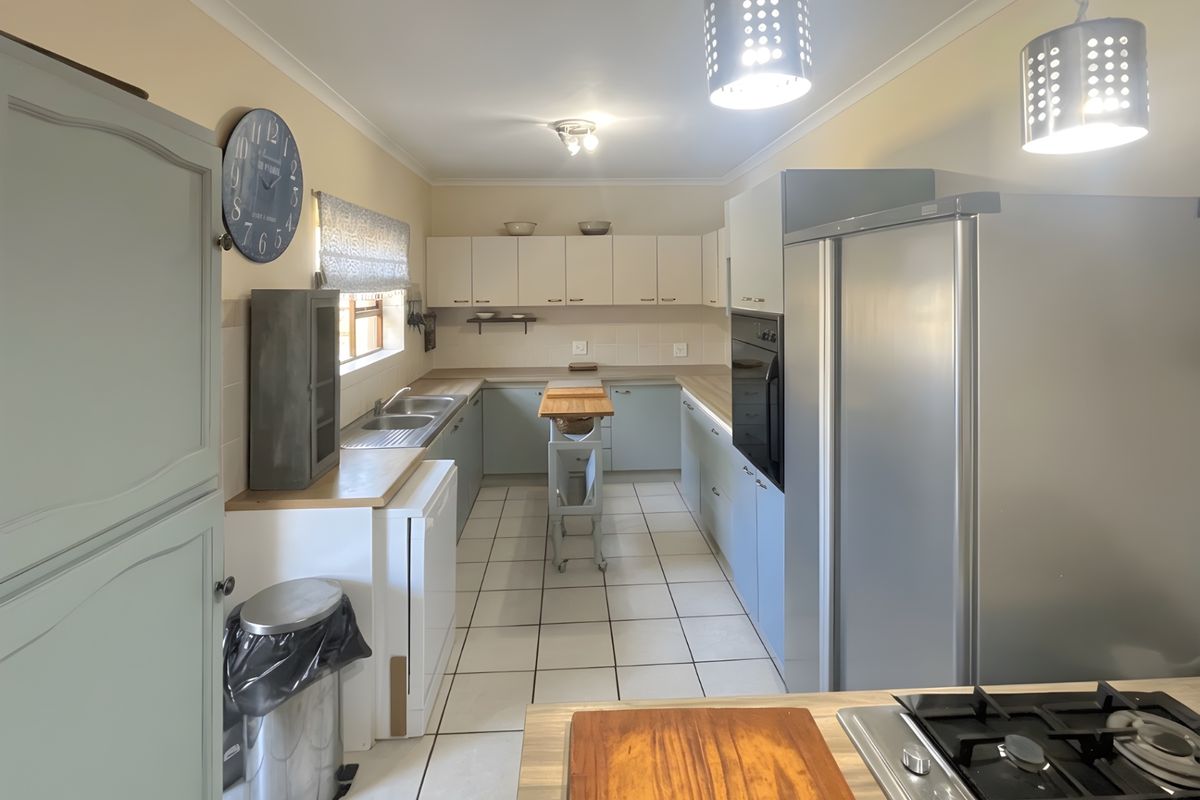 A functional kitchen featuring light-toned cabinetry, tiled flooring, a built-in oven, and a gas hob with ample counter space.