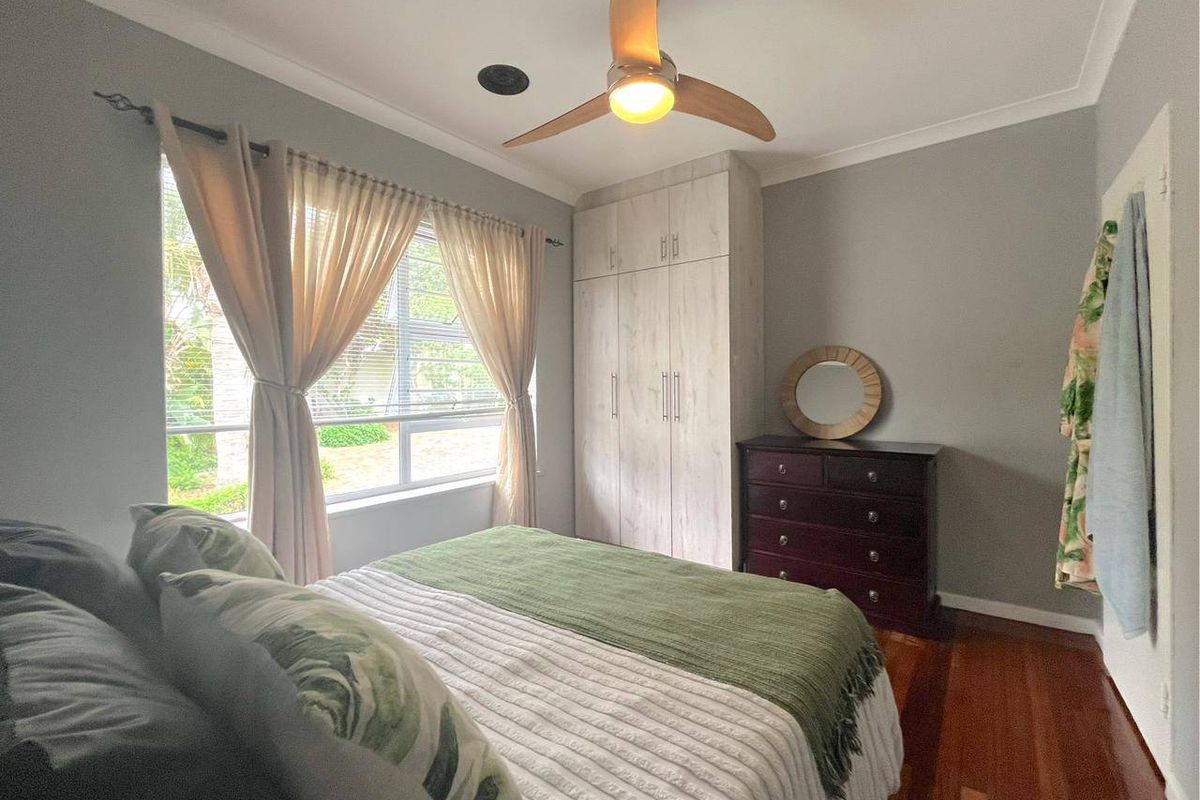 A well-maintained bedroom featuring polished timber flooring, built-in cabinetry, and a ceiling fan, offering a comfortable and functional living space.