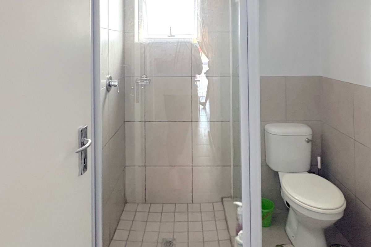 A functional bathroom featuring a glass-enclosed shower with tiled walls and a standard white toilet.