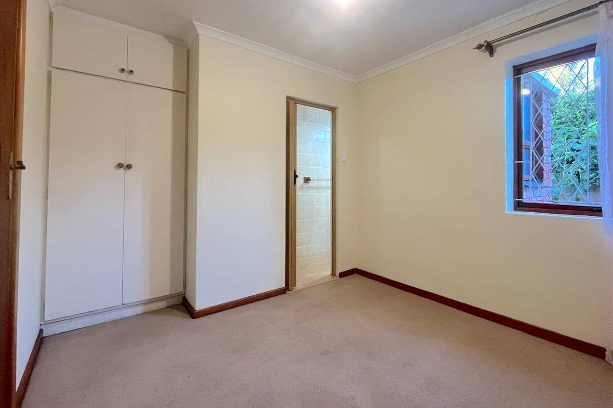 A bedroom featuring built-in cupboards, neutral wall finishes, and an en-suite bathroom access point.