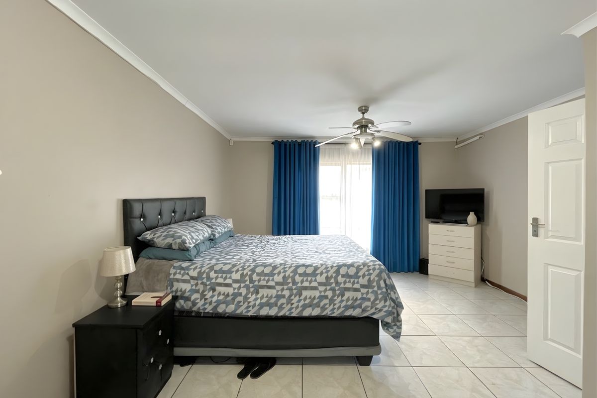 Spacious bedroom featuring neutral wall tones, tiled flooring, a ceiling fan, and direct access to outdoor space through sliding glass doors.