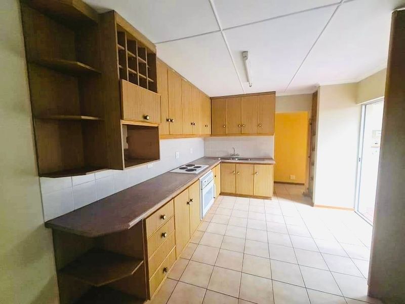 A functional kitchen featuring wood-finish cabinetry, integrated stove and oven, tiled flooring, and direct access to an outdoor area.