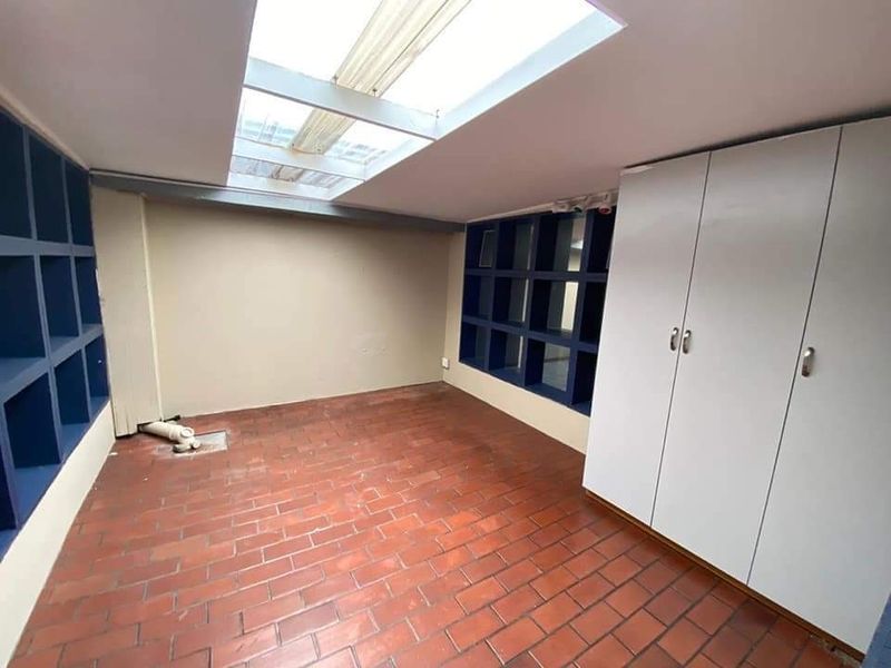 A utility space featuring a skylight, built-in storage cabinetry, and terracotta-style tiled flooring.