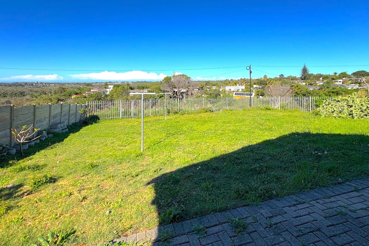 A spacious rear garden featuring a paved patio area, lawn, and perimeter fencing, offering an open outlook over the surrounding neighborhood.