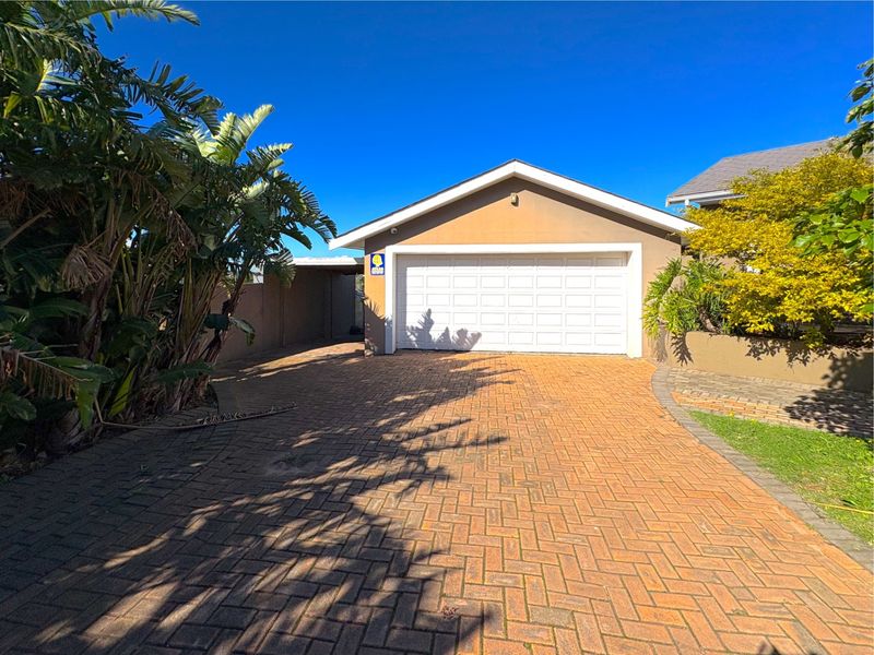 A well-maintained single garage featuring a white sectional door, complemented by a paved driveway and established garden surroundings.