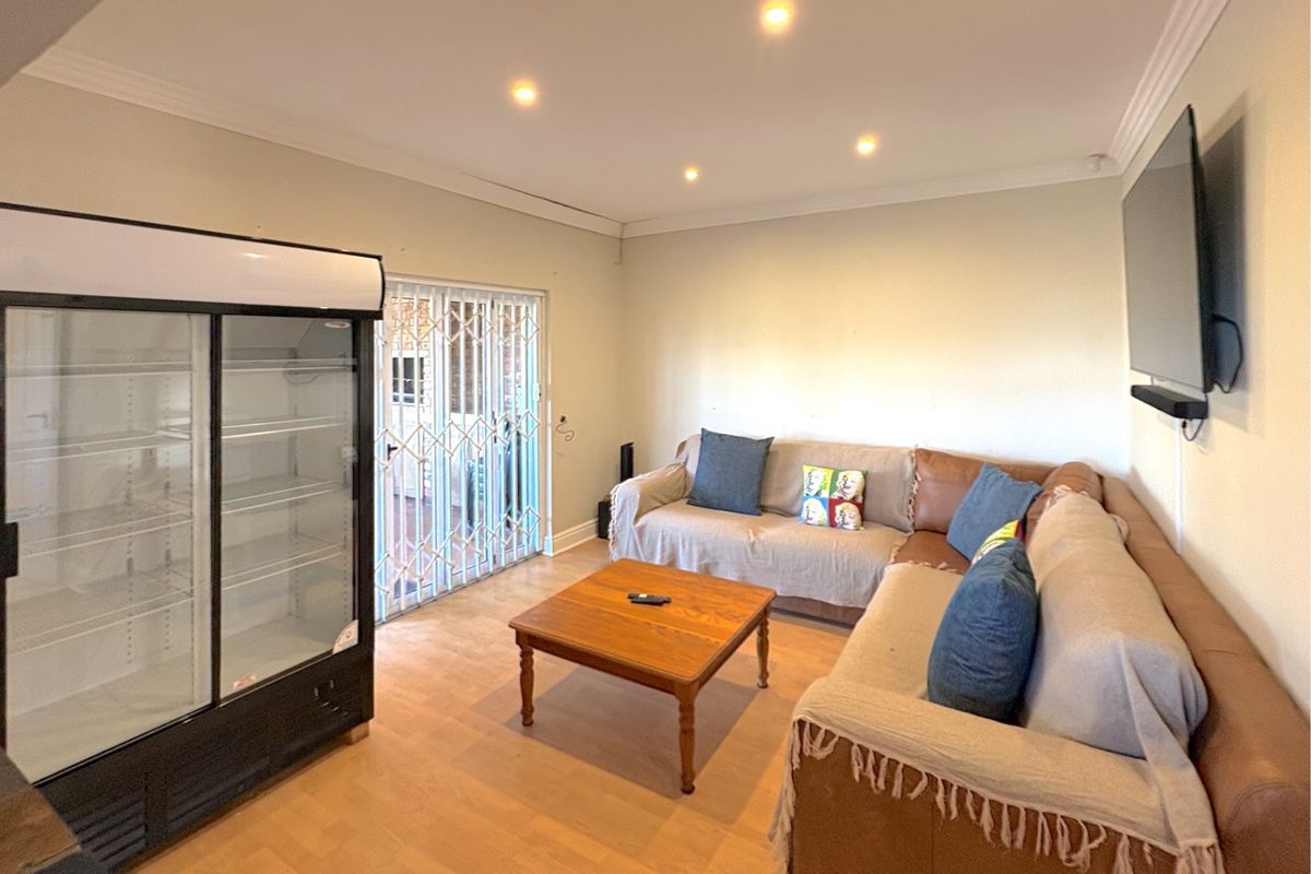 A living room featuring laminate flooring, recessed downlighting, and a security gate leading to the exterior.