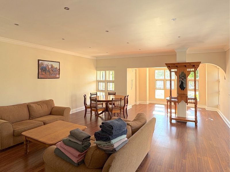 Spacious open-plan living and dining area featuring laminate flooring, recessed downlights, and an architectural archway connecting the two zones.
