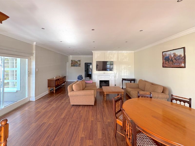 Spacious open-plan living and dining area featuring laminate flooring, a central fireplace, and sliding glass doors leading to the exterior.