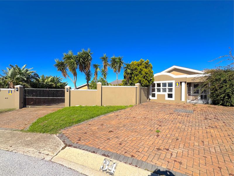 Front exterior view of the property featuring a brick paved driveway, perimeter boundary wall, and secure gated entrance.