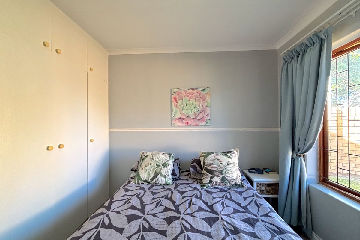 A cozy bedroom featuring built-in floor-to-ceiling cabinetry and a window with natural light.