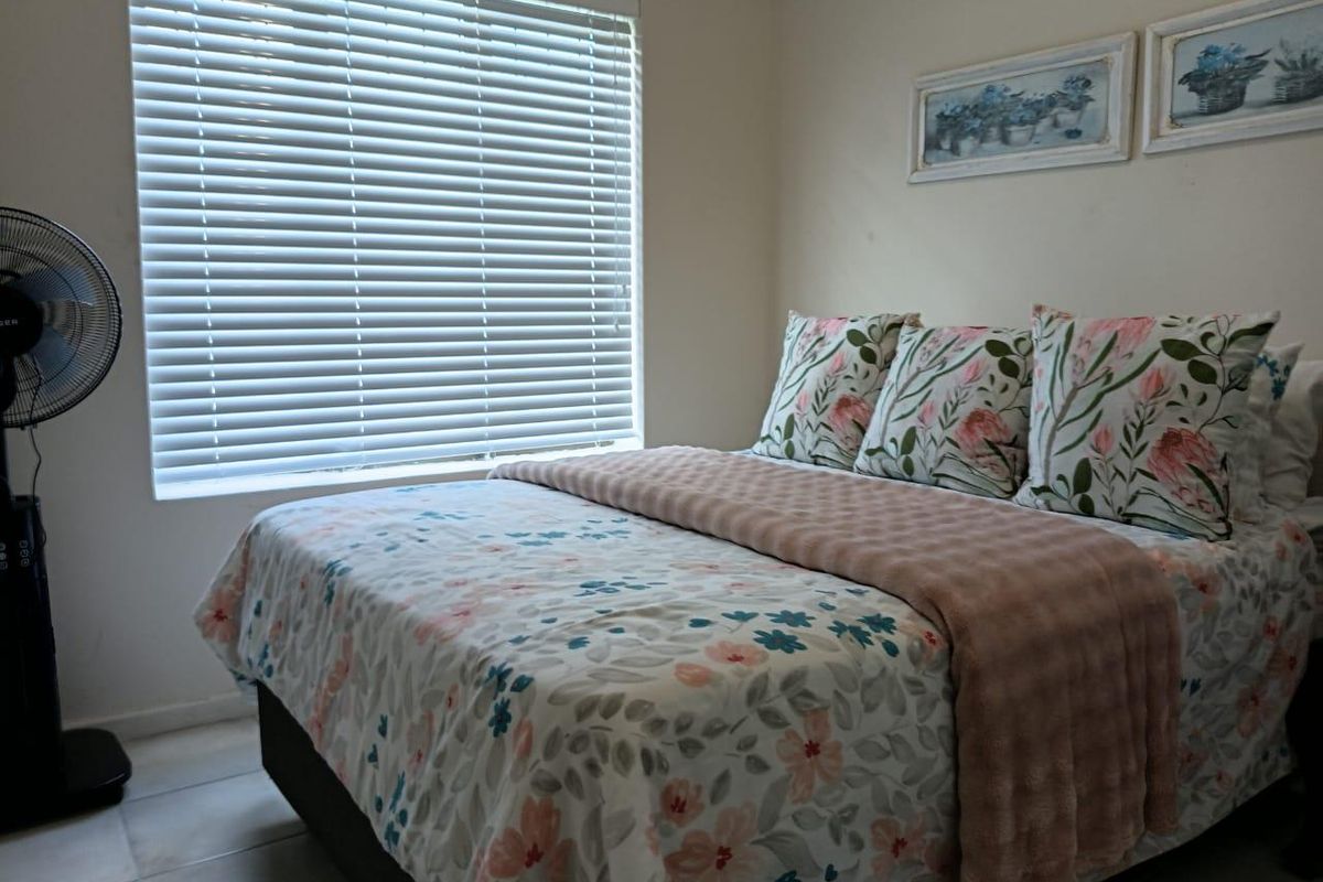 A cozy bedroom featuring tiled flooring and venetian blinds, providing a neutral foundation for personal styling.