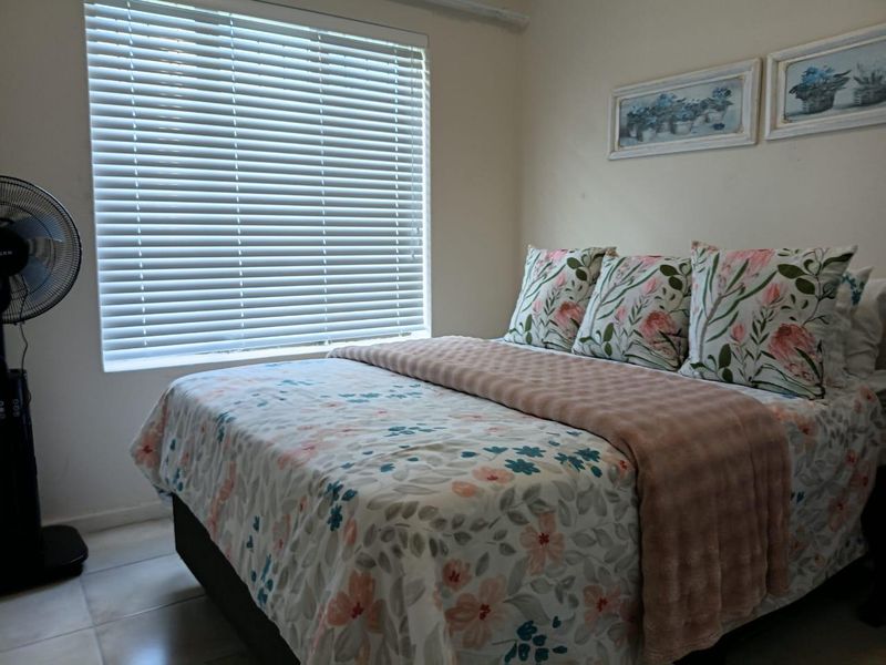 A cozy bedroom featuring tiled flooring and venetian blinds, providing a neutral foundation for personal styling.
