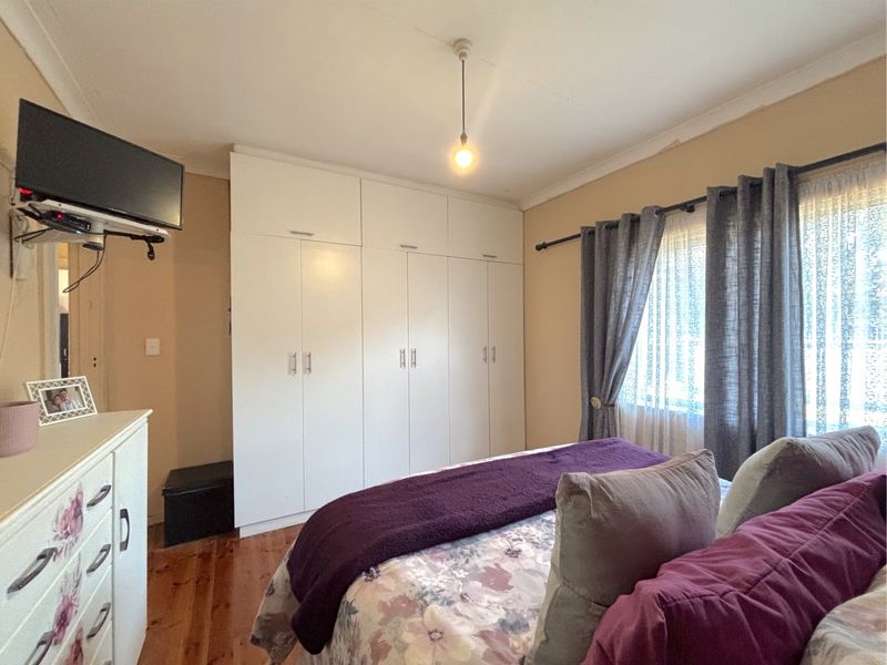A bedroom featuring polished timber flooring and built-in white cabinetry providing ample storage space.