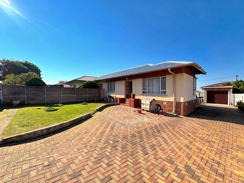 A well-maintained single-story house featuring a paved driveway, a small front lawn, and a detached garage, offering a tidy and functional exterior space.