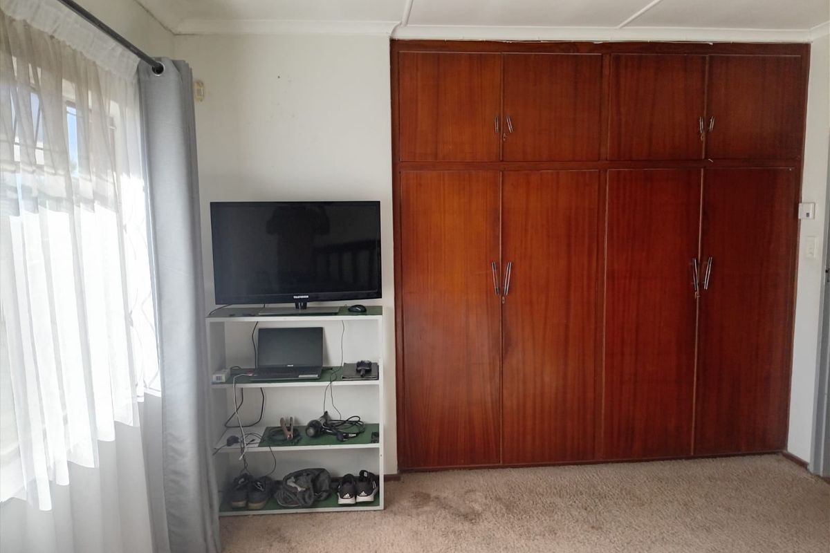 A bedroom featuring built-in wooden cupboards and carpeted flooring, providing ample storage space.