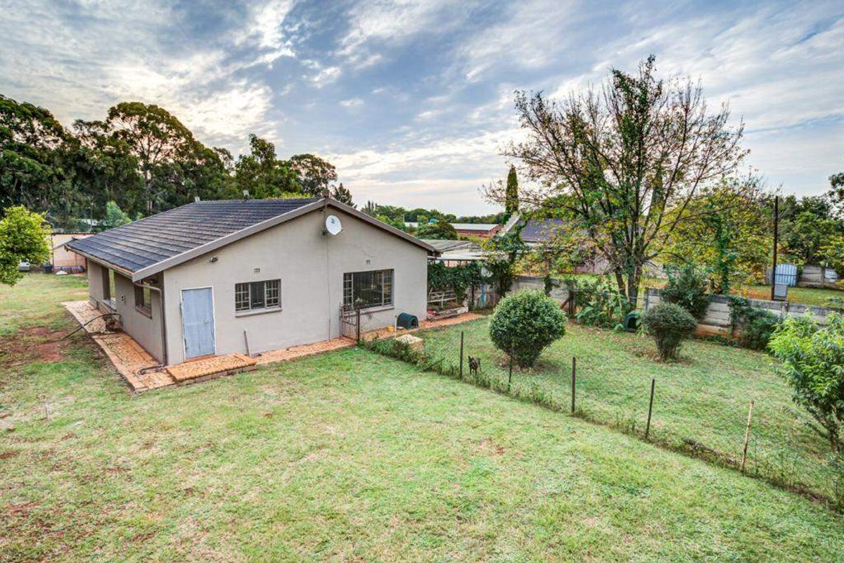 Rear view of the farm property featuring a tiled roof, brick exterior, and a spacious garden area with perimeter fencing.