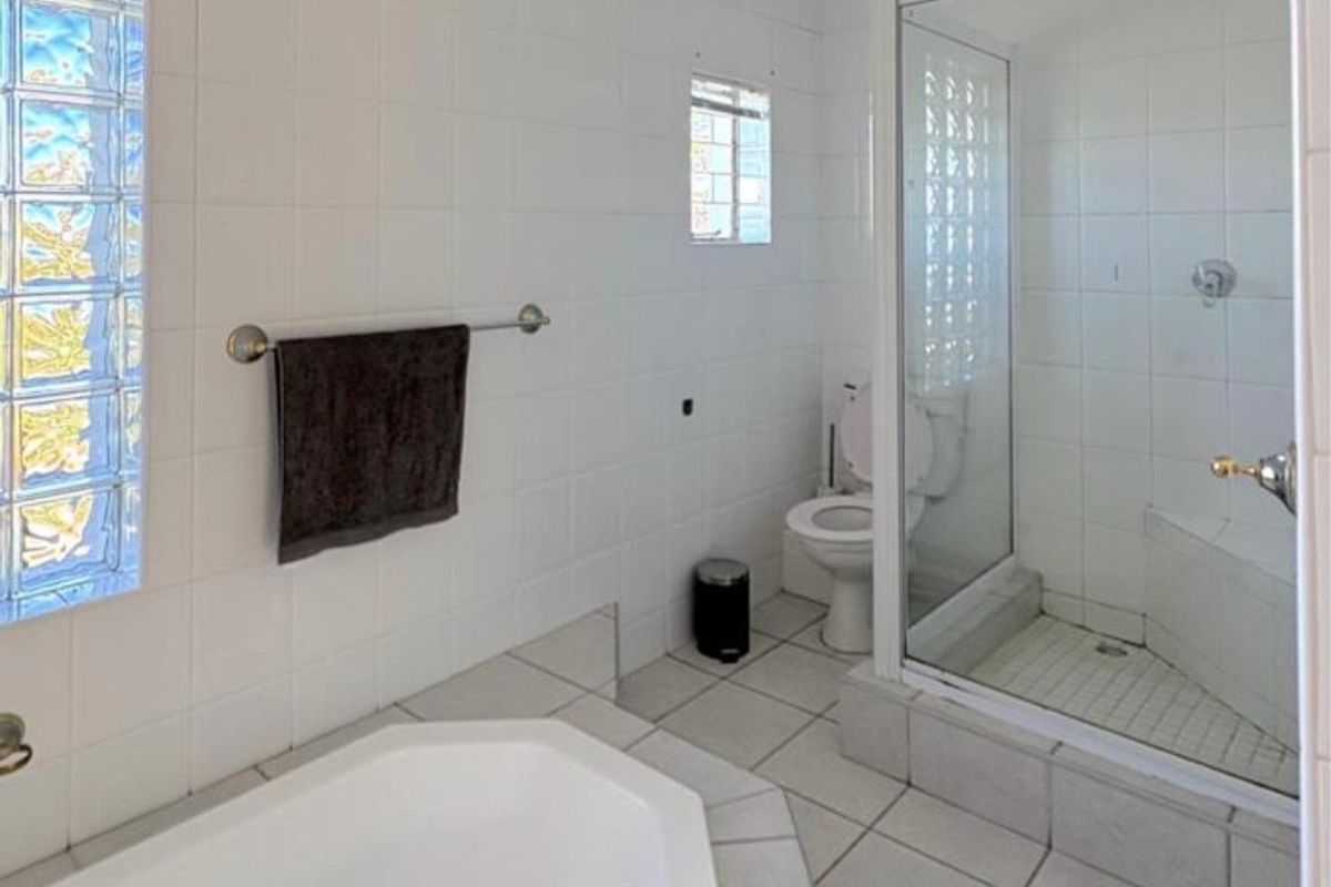A functional bathroom featuring a built-in corner bathtub, a separate glass-enclosed shower, and glass block windows for natural light.