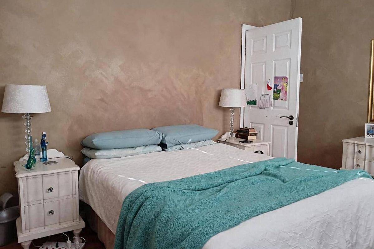 A bedroom featuring timber flooring and a classic panelled door, with textured wall finishes.