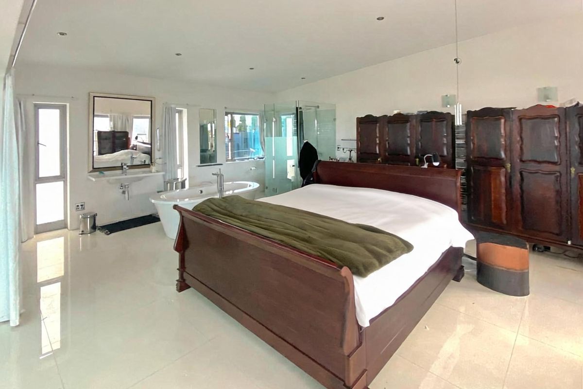 Spacious open-plan bedroom featuring an integrated en-suite bathroom with a freestanding bathtub, glass-enclosed shower, and wall-mounted basin.