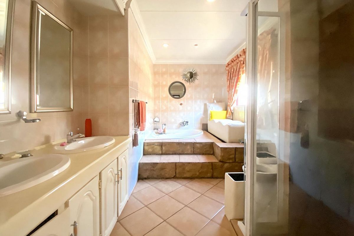Spacious bathroom featuring a raised platform with a built-in soaking tub, dual vanity unit, and a separate glass-enclosed shower area.