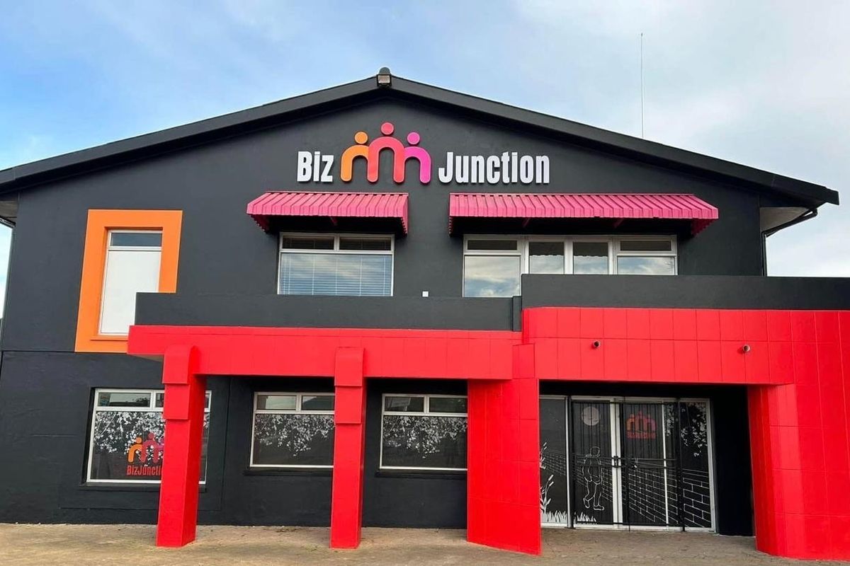 Front facade of a commercial building featuring a prominent entrance, modern signage, and a bold red and black exterior color scheme.