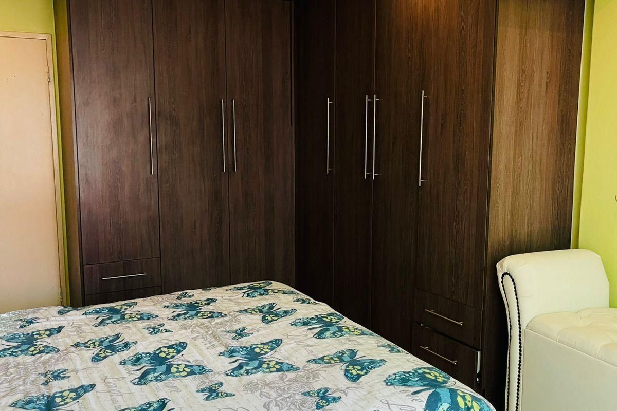 A bedroom featuring built-in dark wood cabinetry with integrated storage and a decorative ceiling cornice.