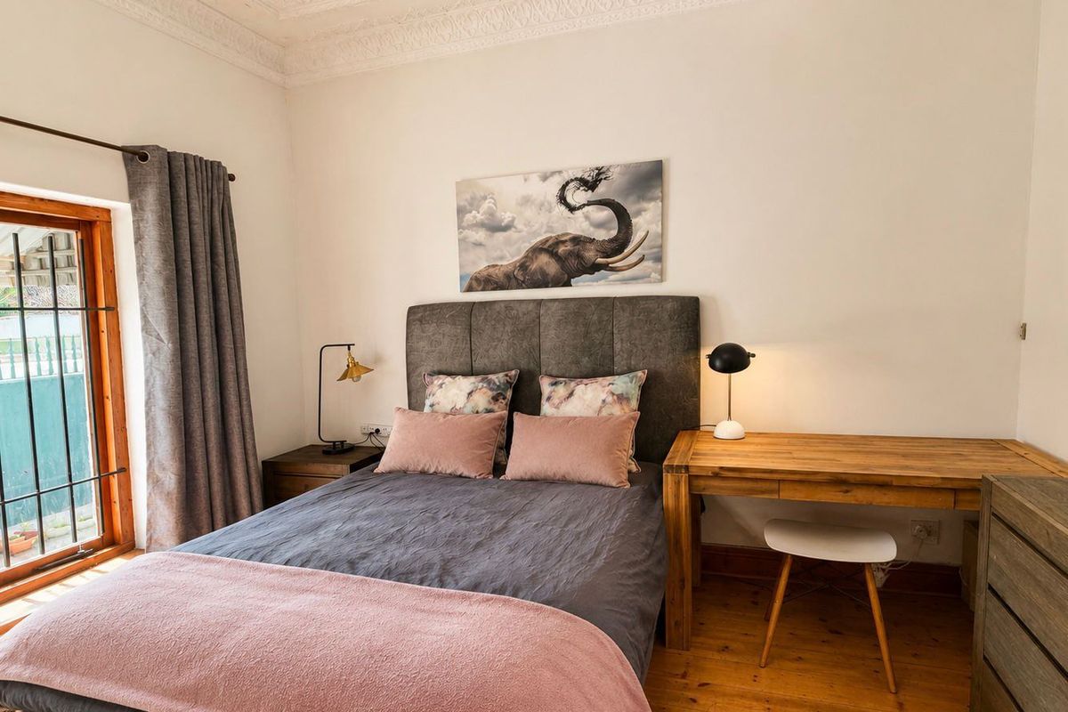 A well-maintained bedroom featuring polished timber flooring, ornate ceiling cornicing, and a glass door providing access to the exterior.