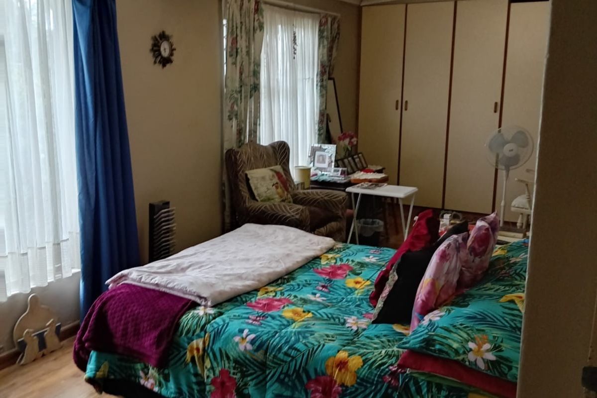 A bedroom featuring built-in wardrobes, laminate flooring, and large windows allowing natural light.