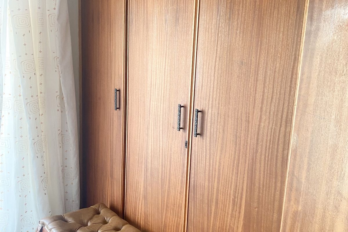 A bedroom featuring floor-to-ceiling built-in wooden cabinetry with integrated storage compartments.