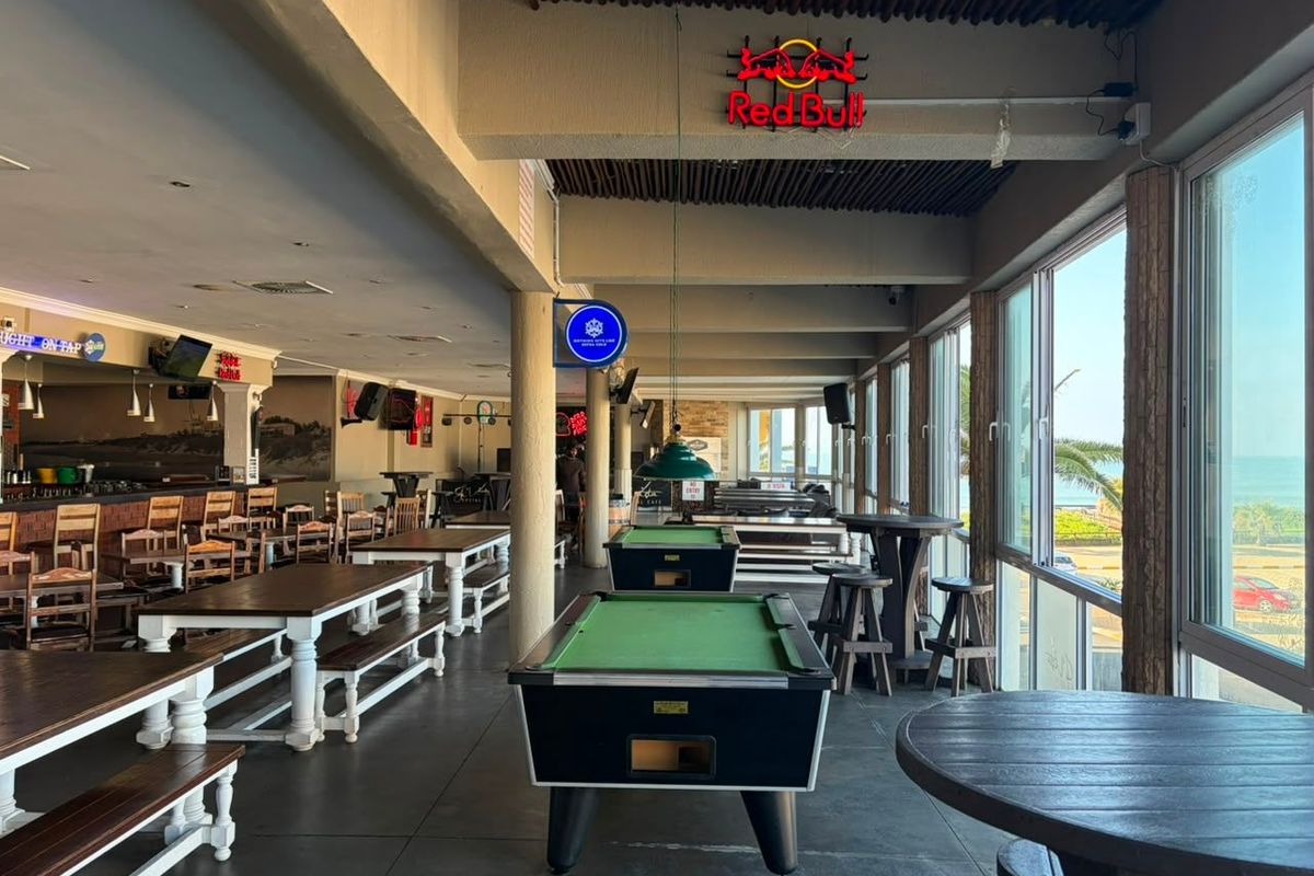 Spacious commercial bar and entertainment area featuring pool tables, built-in bar counter, and large windows with scenic exterior views.