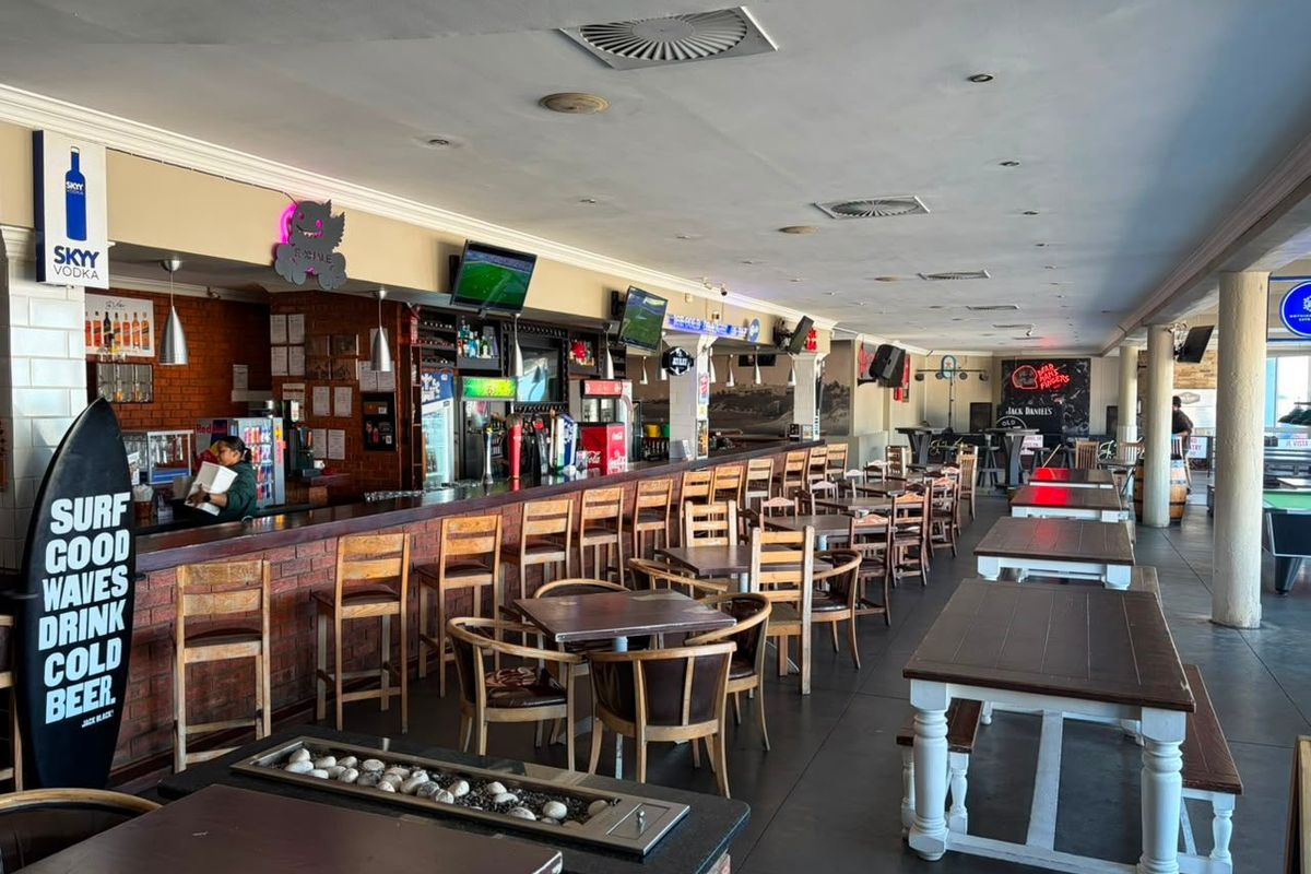 Spacious commercial bar area featuring a long brick-faced service counter, integrated ceiling lighting, and ample seating space for patrons.
