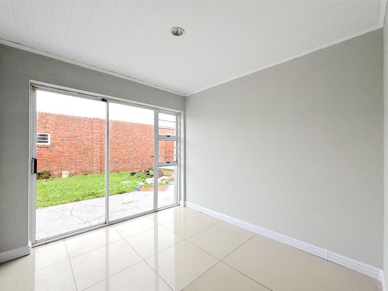 A bright, empty living area featuring large sliding glass doors that provide natural light and direct access to the rear garden.