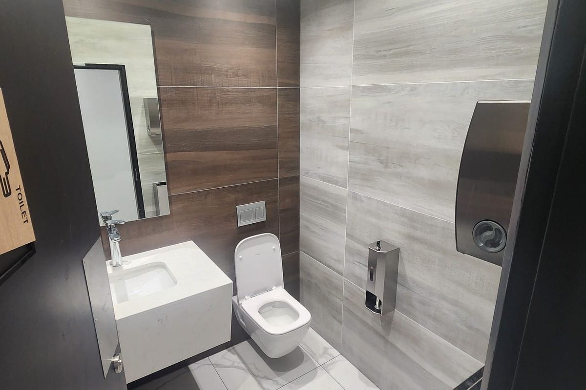 Modern industrial-style restroom featuring a wall-mounted vanity, sleek white toilet, and contemporary wood-look tile wall finishes.