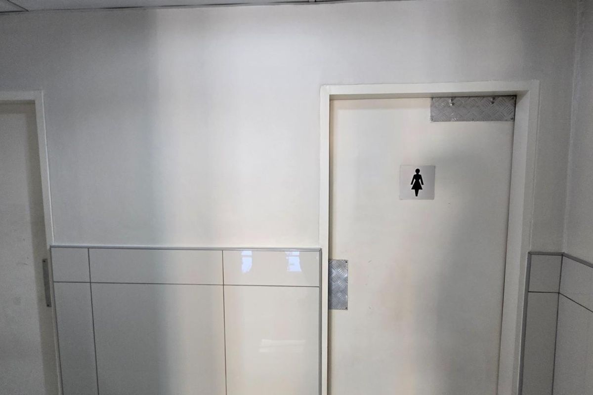 Commercial restroom facility featuring separate male and female access doors with tiled lower wall finishes.