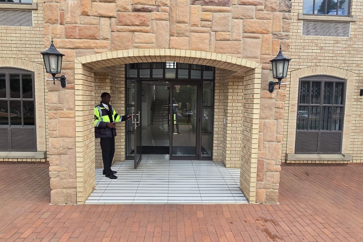 Main entrance of a commercial building featuring a stone-clad arched portico, brick facade, and paved exterior walkway.