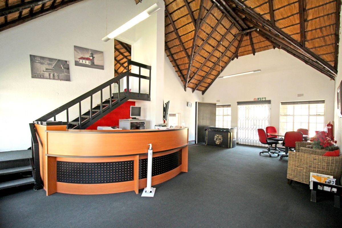 Spacious open-plan area featuring a high exposed thatch ceiling, a built-in reception desk, and a staircase leading to an upper level.
