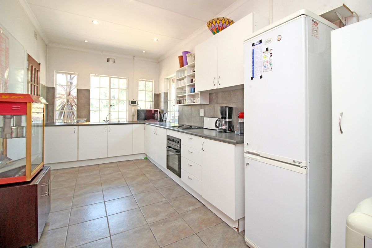 Functional kitchen featuring white cabinetry, laminate countertops, built-in oven, hob, and tiled flooring with ample natural light from multiple windows.