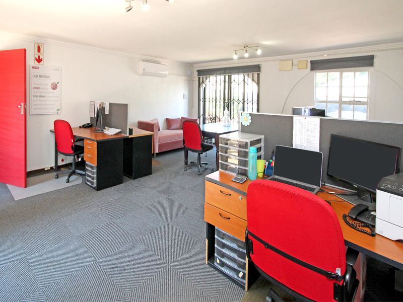 A functional office space featuring carpeted flooring, a split-system air conditioner, and security features, suitable for a professional work environment.
