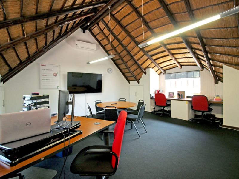 Spacious office area featuring a high vaulted thatched roof with exposed timber rafters, built-in desk space, and wall-mounted air conditioning.