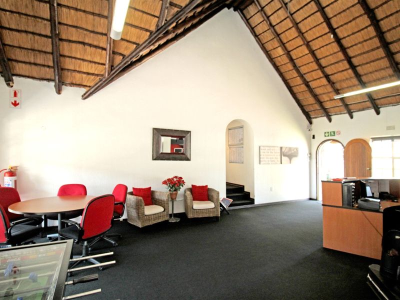 Spacious living area featuring a high vaulted thatch ceiling, arched architectural details, and a built-in reception desk, offering a unique rustic aesthetic.