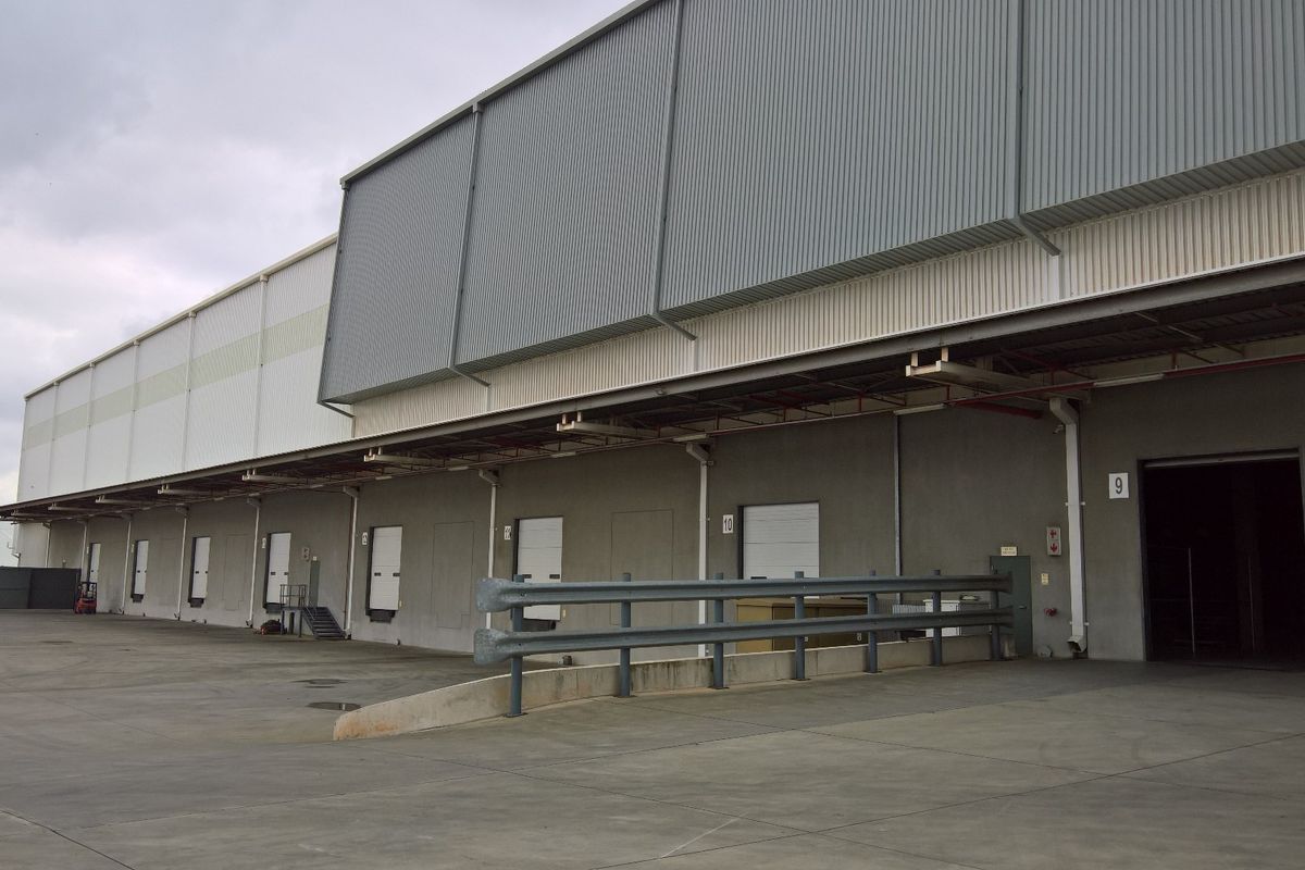 Industrial warehouse exterior featuring multiple loading bays, concrete apron, and metal cladding facade.