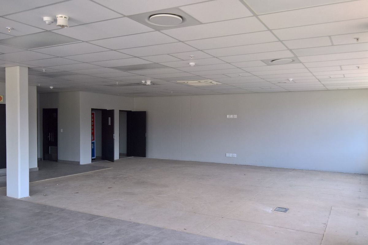A spacious, open-plan industrial office area featuring a suspended ceiling, recessed lighting, integrated air conditioning, and functional electrical floor access points.