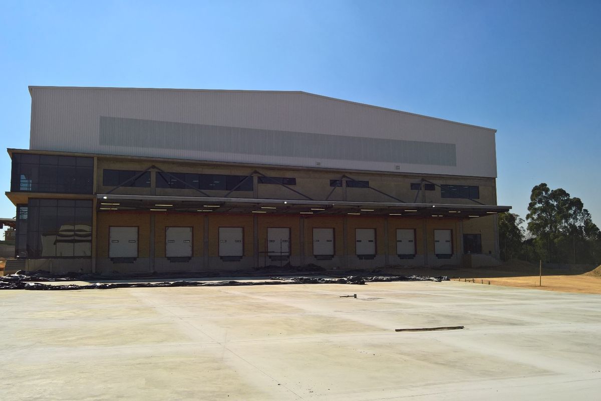 Modern industrial warehouse facility featuring multiple loading docks, a large concrete yard, and high-clearance metal cladding construction.