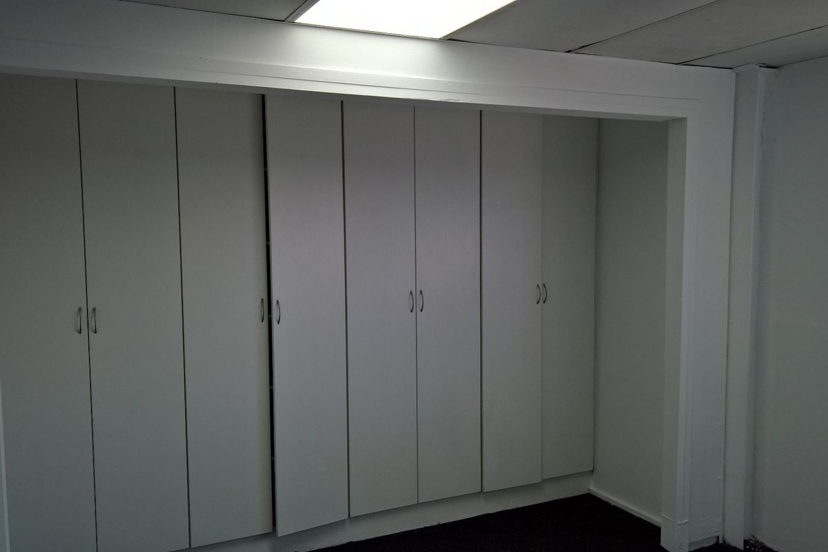 A functional utility space featuring extensive built-in cabinetry and recessed ceiling lighting, providing ample storage capacity for industrial or office use.