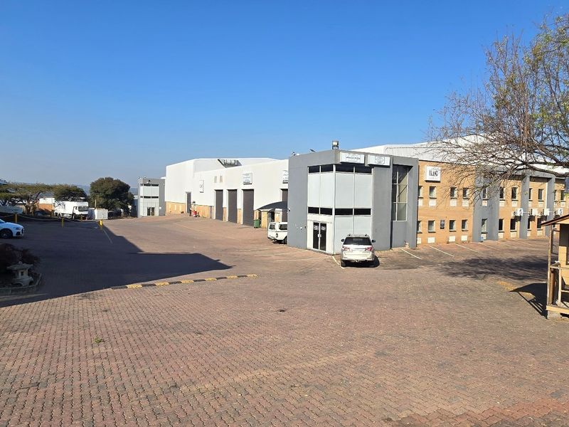 Wide-angle view of an industrial park complex featuring multiple warehouse units, paved yard space, and a security guard hut at the entrance.