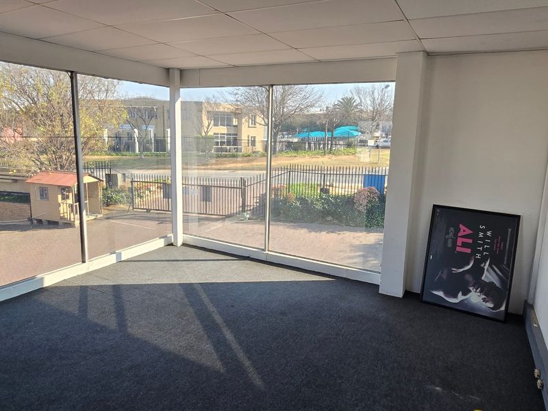 Empty office space featuring large floor-to-ceiling windows providing ample natural light and views of the surrounding industrial complex.