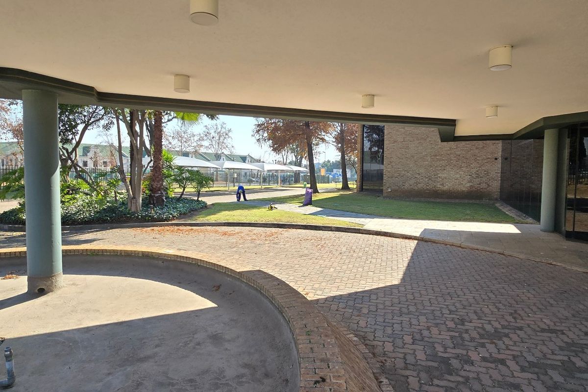A covered entrance area featuring brick paving, concrete columns, and a glass facade, providing a professional approach to the industrial property.