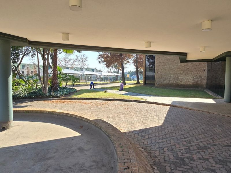 A covered entrance area featuring brick paving, concrete columns, and a glass facade, providing a professional approach to the industrial property.