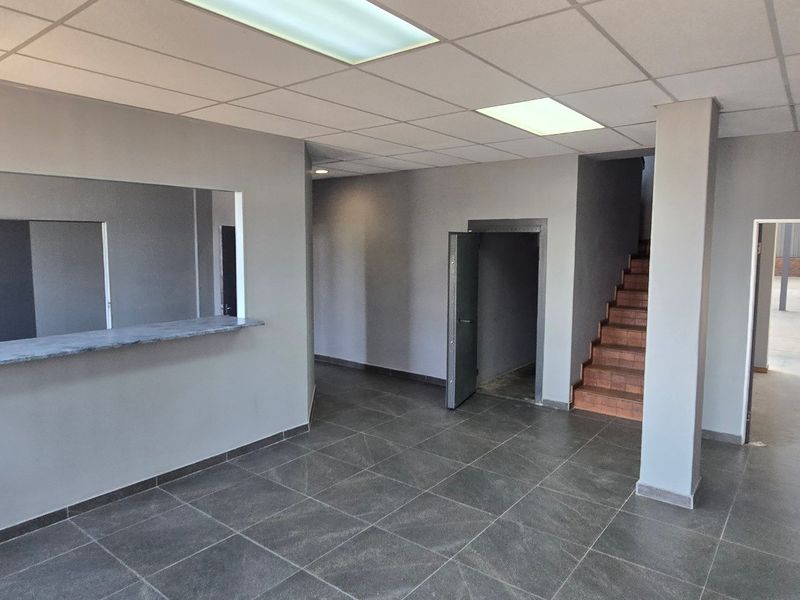 A clean, modern industrial entry area featuring tiled flooring, a service counter, and a staircase leading to an upper level.
