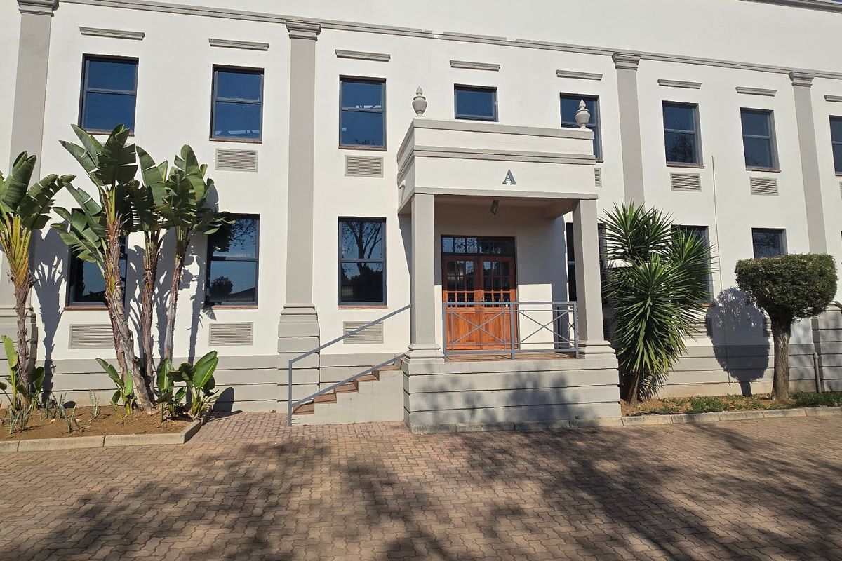 Front elevation of a professional industrial building featuring a covered entrance portico, paved driveway, and symmetrical architectural detailing.